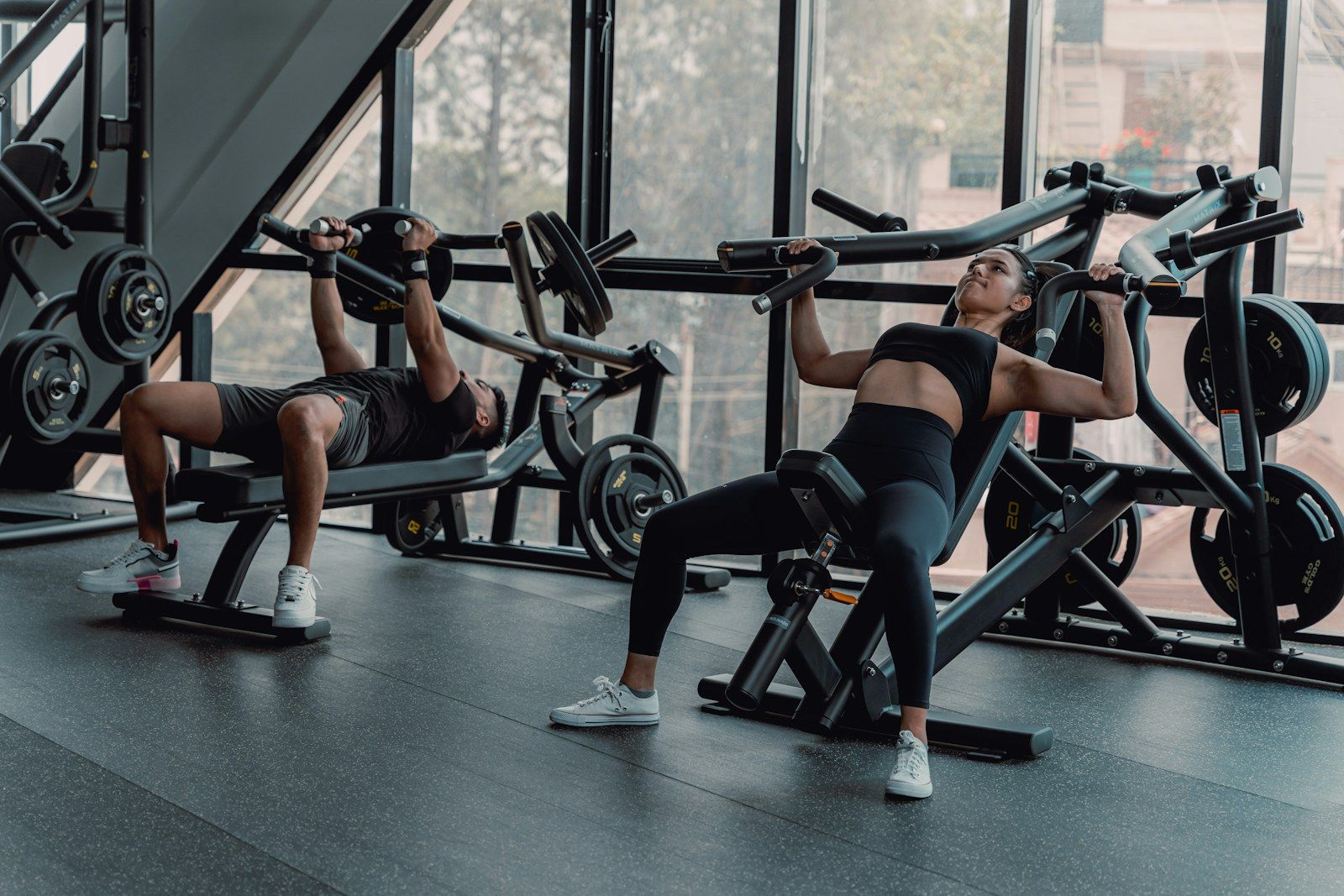 Dos personas entrenando con máquinas de fuerza en un gimnasio