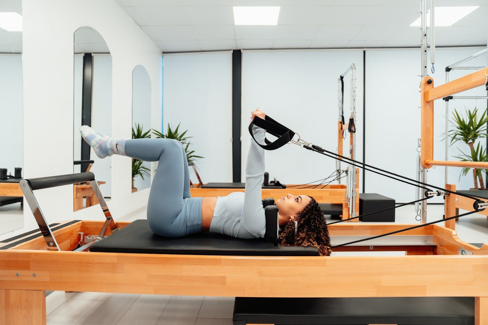 Alumna haciendo un ejercicio con correas en un reformer de Pilates